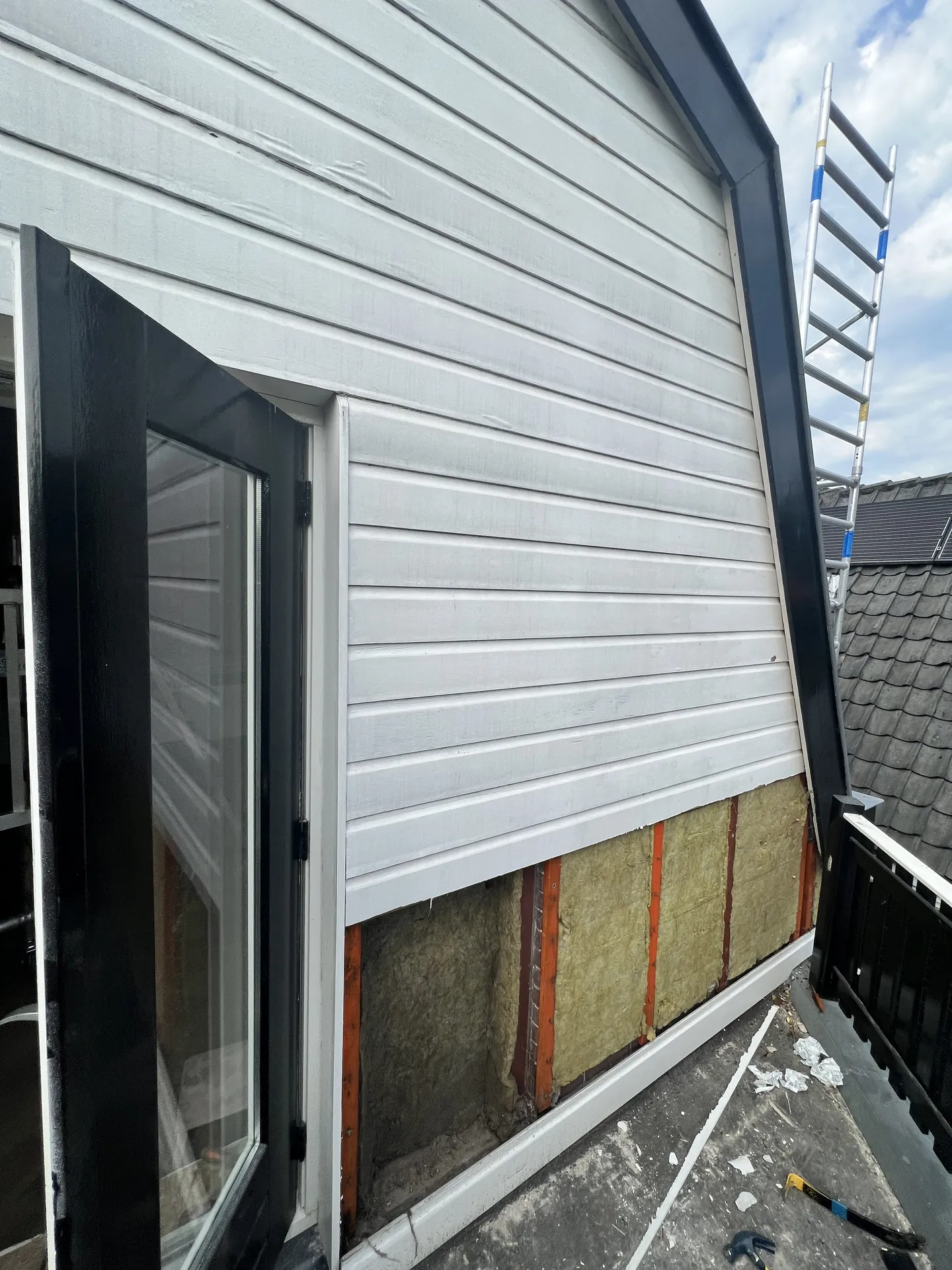 Gevel met minerale wol isolatie achter de nieuwe witte gevelbekleding