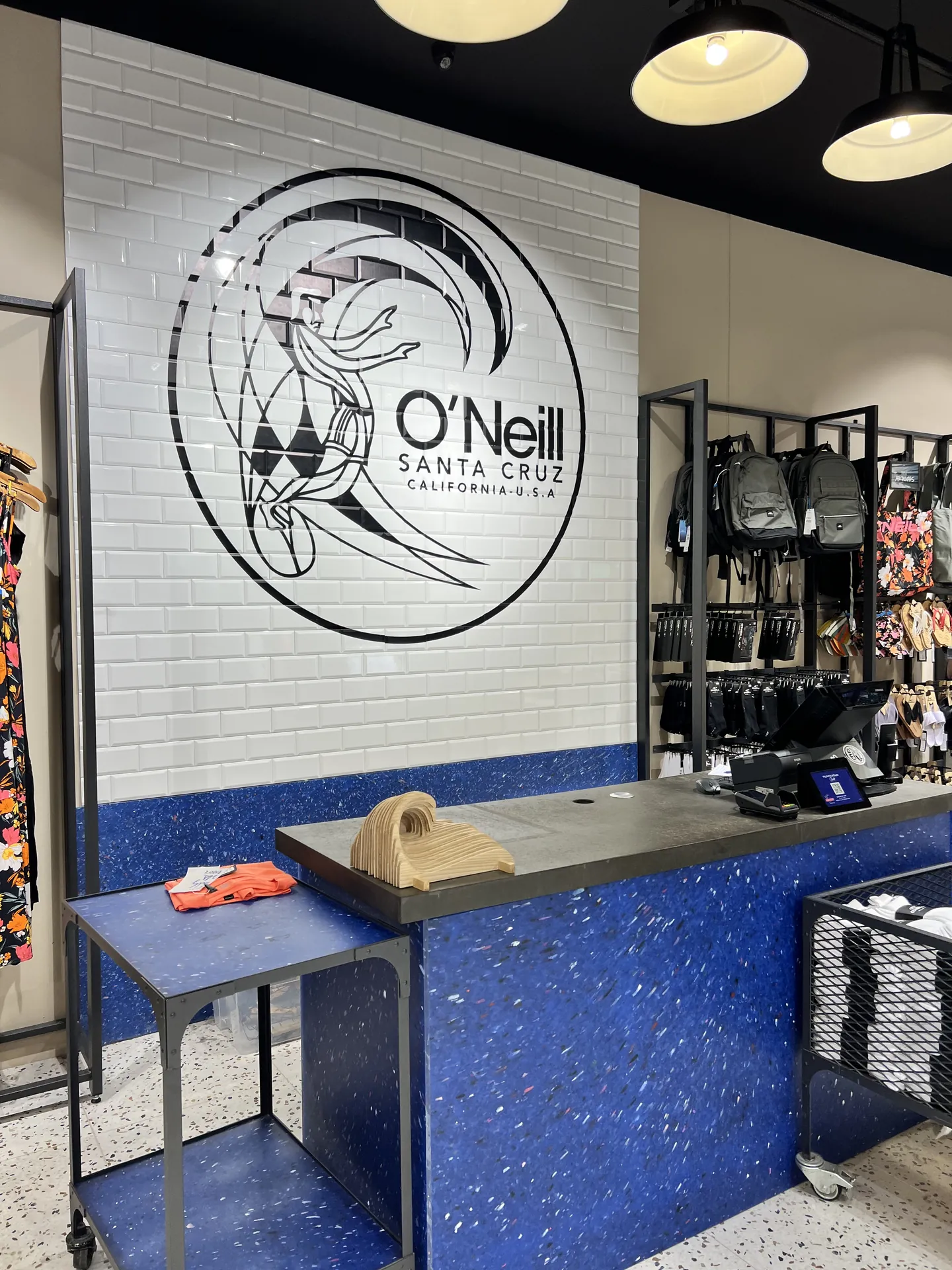 Servicebalie van blauw gerecycled materiaal en tegelwand met O'Neill-logo