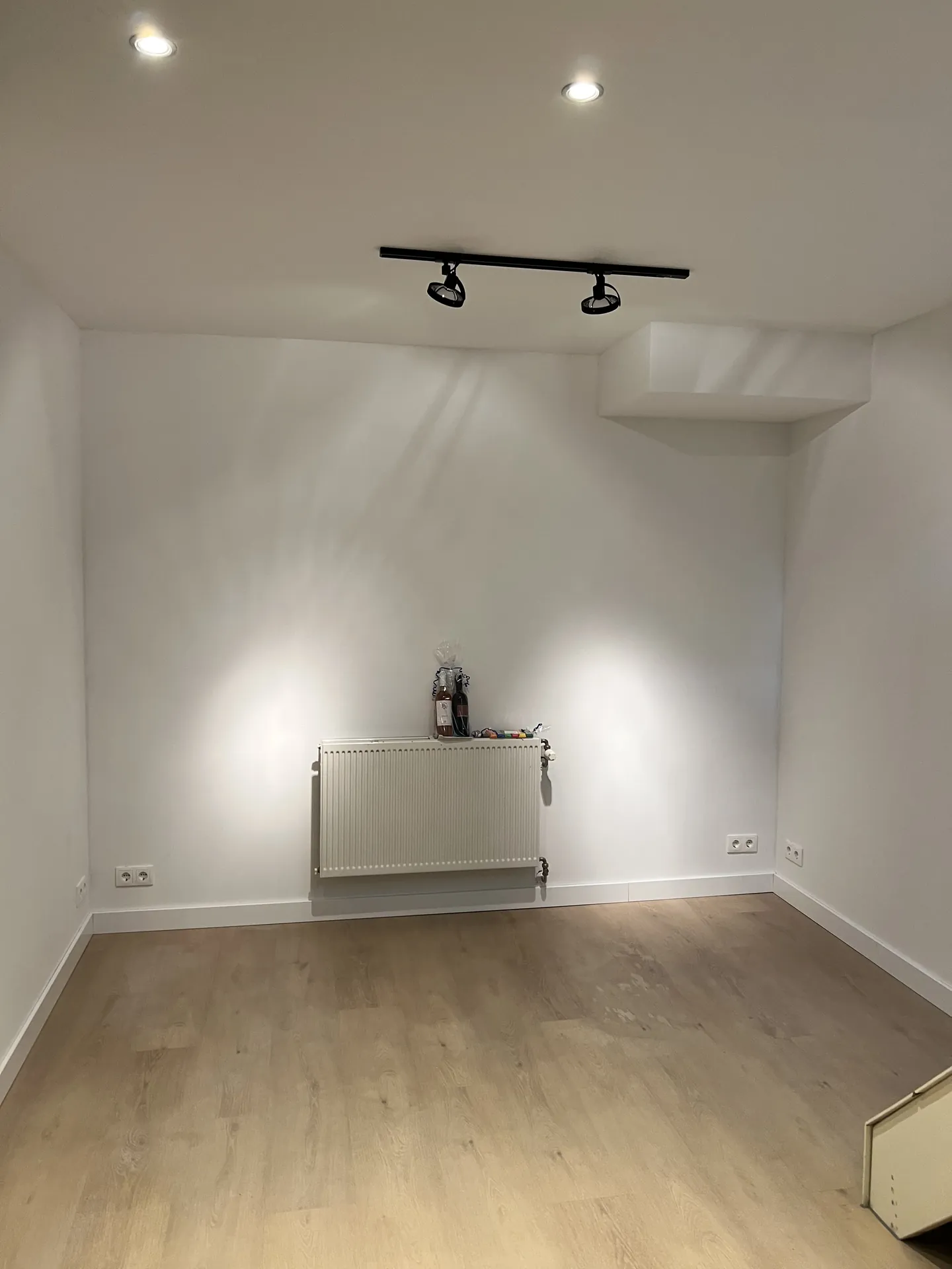 Witte ruimte met railverlichting, radiator en nieuwe vloer