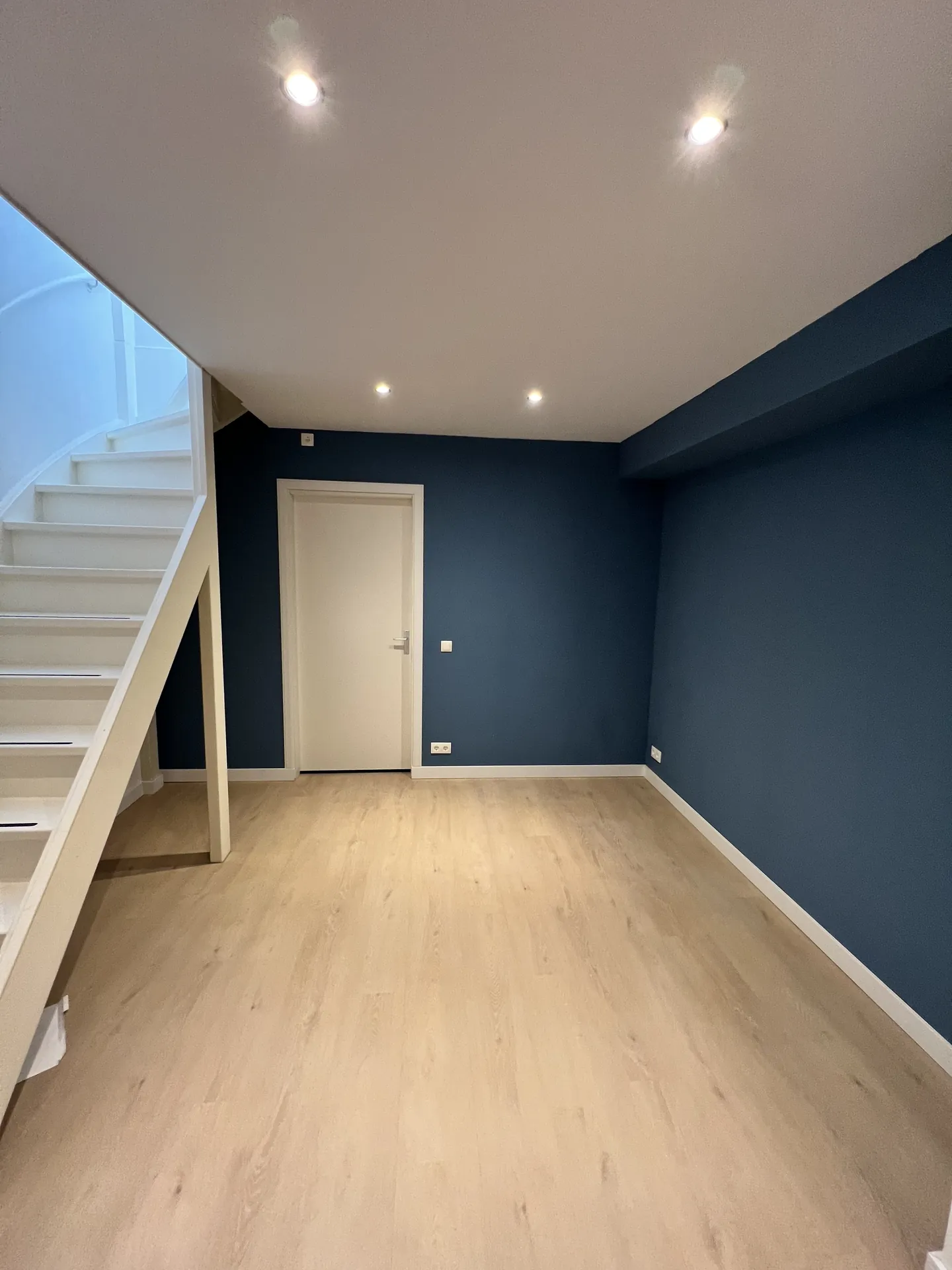 Ruimte met trap, blauwe accentwand en inbouwspots