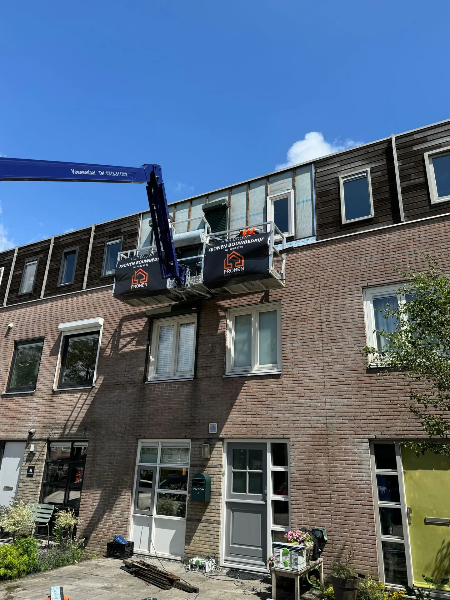 Rij woningen in Velserbroek met hoogwerker tijdens de gevelrenovatie